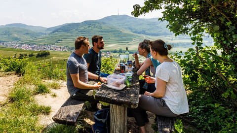 Eine Gruppe Wanderer macht auf einer Bank Pause | Tipps für Ausflüge & Veranstaltungen an Pfingsten in Rheinland-Pfalz