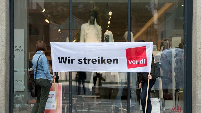 Zwei Frauen stehen in Stuttgart mit einem Transparent mit der Aufschrift "Wir streiken verdi"