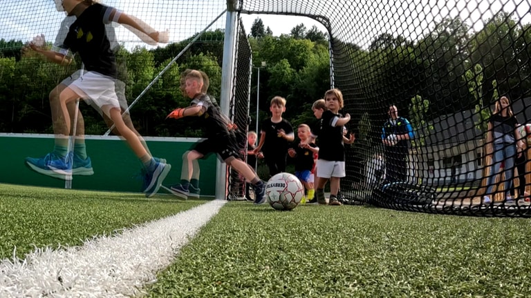 Die Bambinis des SV Dernau rennen in ihren mobilen Spielkäfig. 