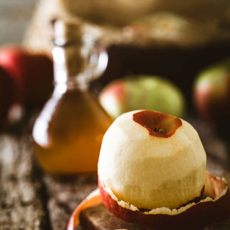 Apfel und Flasche Apfelessig auf Holz