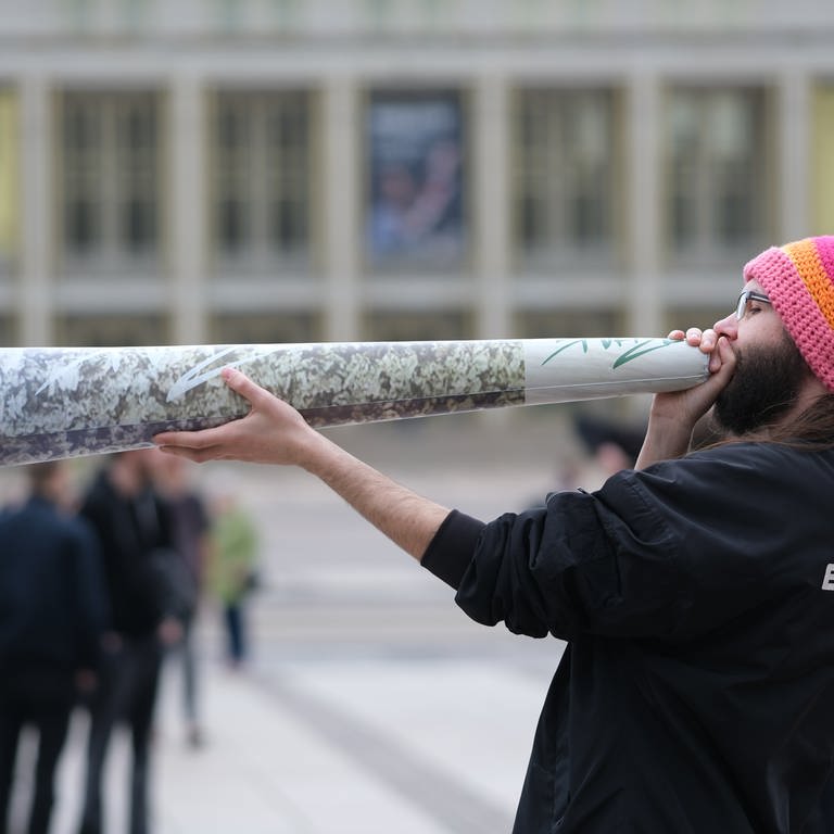 Ein Teilnehmer einer Kundgebung hält einen überdimensionierten Joint in den Händen. Ab dem 1. April 2024 ist Erwachsenen ab 18 Jahren der Besitz von 25 Gramm im öffentlichen Raum erlaubt.