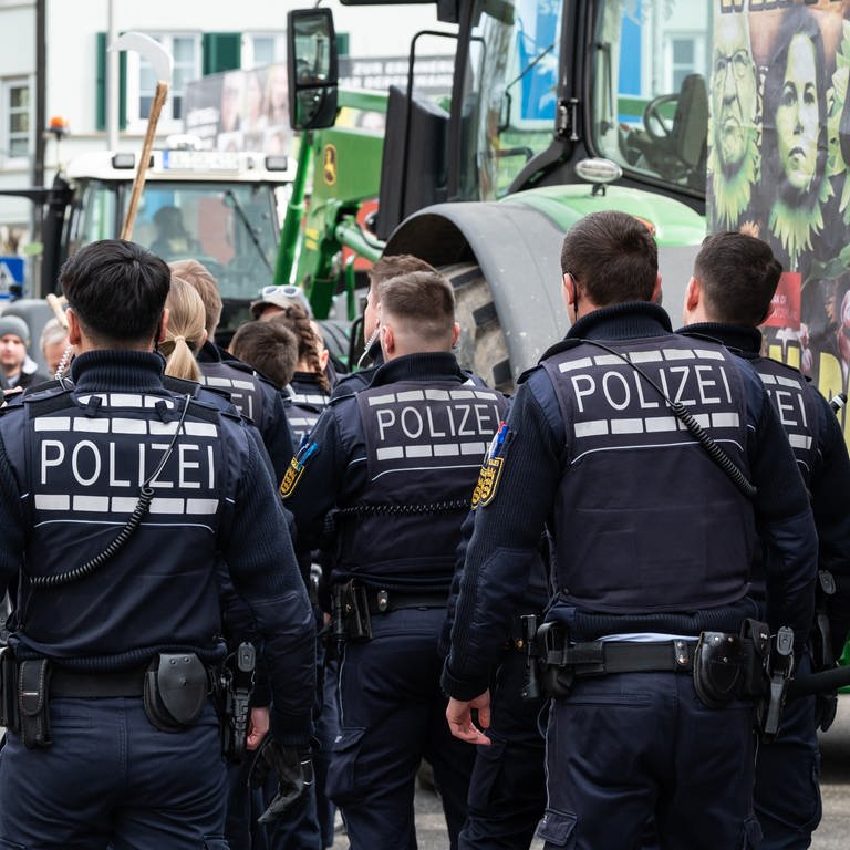 Polizisten gehen während einer Demonstration vor Beginn des politischen Aschermittwochs der baden-württembergischen Grünen vor der Stadthalle in Biberach an der Riß.