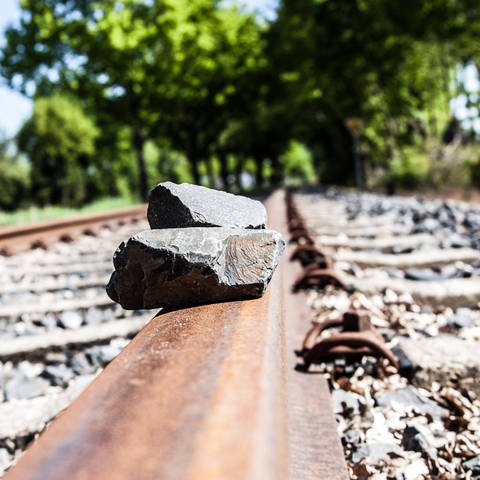 Auf den Gleisen einer Bahnstrecke liegen auf den Schienen Steine (Symbolbild).