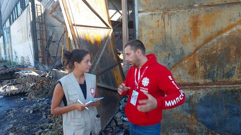 Mitarbeiter von Caritas International vor zerstörtem Lagerhaus in Lwiw