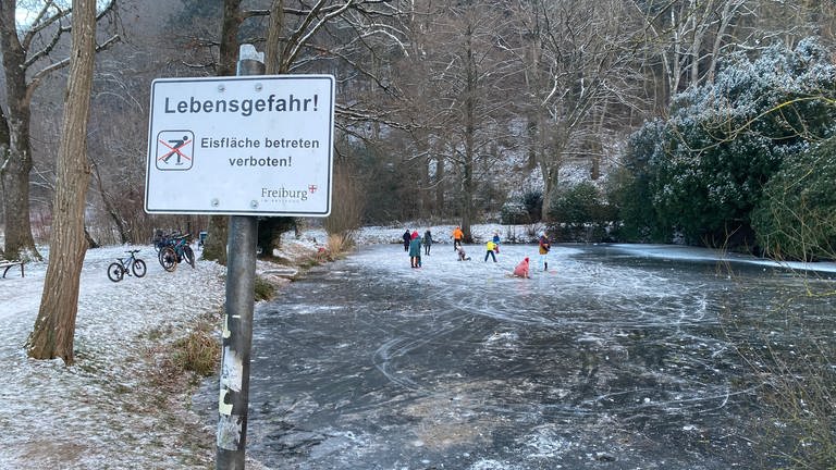 Menschen mit Schlittschuhen auf einen zugefrohrenen Teich in Freiburg
