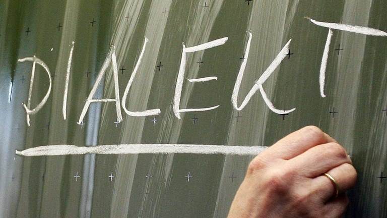 Das Wort "Dialekt" steht auf einer Tafel. Eine Studie hat die Dialekte bei Grundschülerinnen und Gründschülern in Baden-Württemberg untersucht.
