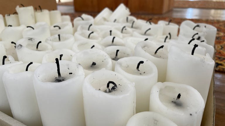 Dutzende weiße, bereits vewendete Kerzen in einem Karton im Kloster Neresheim. Ihr Wachs wird für sogenannte Büchsenlichter weiterverwendet, die in die Ukraine geliefert werden. 