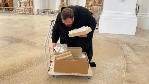 Bruder Matthias sammelt ausgediente Kerzen im Kloster Neresheim und stellt auf einen Wagen. Das Wachs der Kerzhen wird in die Ukraine gebracht, wo es dann zu Büchsenlichtern weiterverarbeitet wird. 