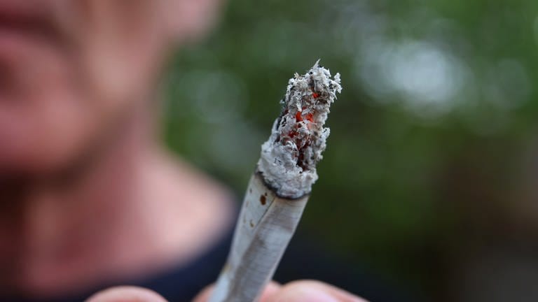 Ein Mann hält einen Joint. Ab dem 1. April ist durch das Cannabis-Gesetz der Konsum der Droge teilweise erlaubt.