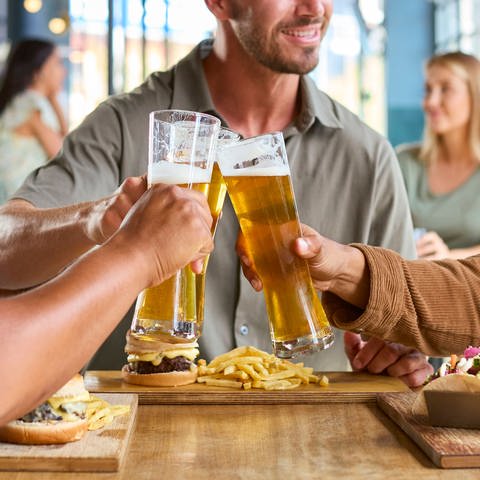 Drei Männer stoßen mit Bier an - auch bei der Berg Brauerei in Ehingen boomt das Geschäft mit alkoholfreiem Bier. (Symbolbild)
