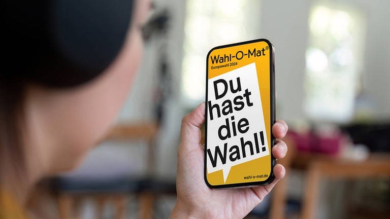 Europawahl 2024 Wahl-O-Mat ist online: Hand hält Smartphone mit Wahl-O-Mat-App