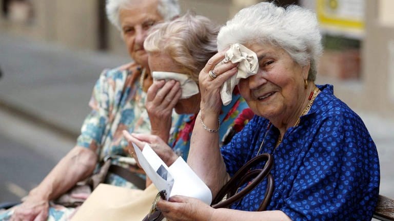 Drei alte Frauen wischen sich den Schweiß von der Stirn