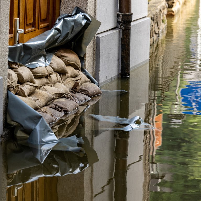 Sandsäcke vor einem Hauseingang in einer überfluteten Straße