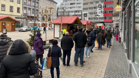 Menschen warten vor einer Teststation in Kaiserslautern auf ihren Schnelltest