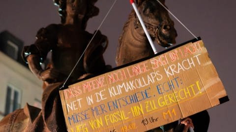 Die Letzte Generation hat der Figur von St. Martin auf der Mainzer Kupferbergterrasse ein Schild mit einem Spruch umgehängt.