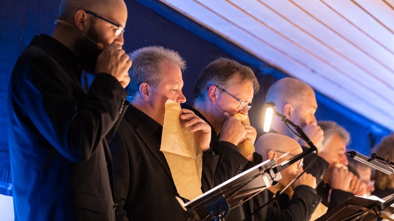 Die Sänger des SWR Vokalensembles singen bei den Donaueschinger Musiktage mit Papier vor dem Mund