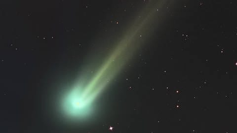 Ein Komet mit grünem Kopf und gelblichem Schweif.